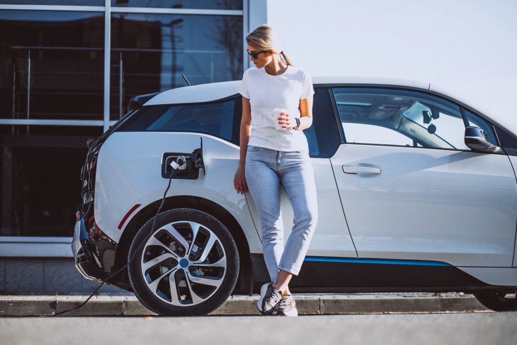 Woman leans up against an electric cars