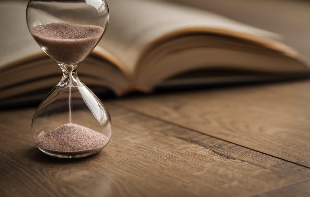 A bible and hourglass on a table signifying the end times.