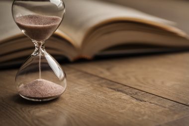 A bible and hourglass on a table signifying the end times.