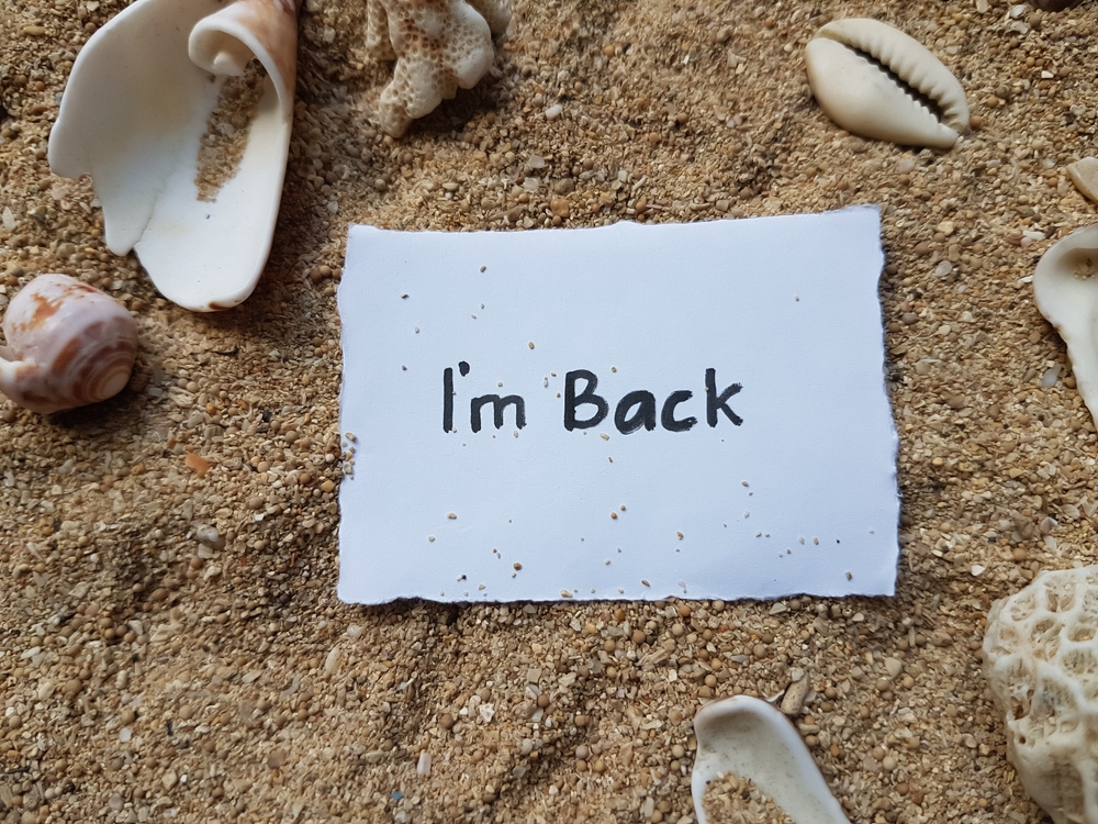 Note on sandy beach that says I'm Back.