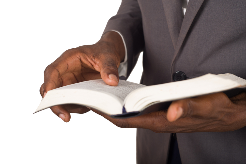 A bible teachers holds a bible open to prepare for exposition of God's word.